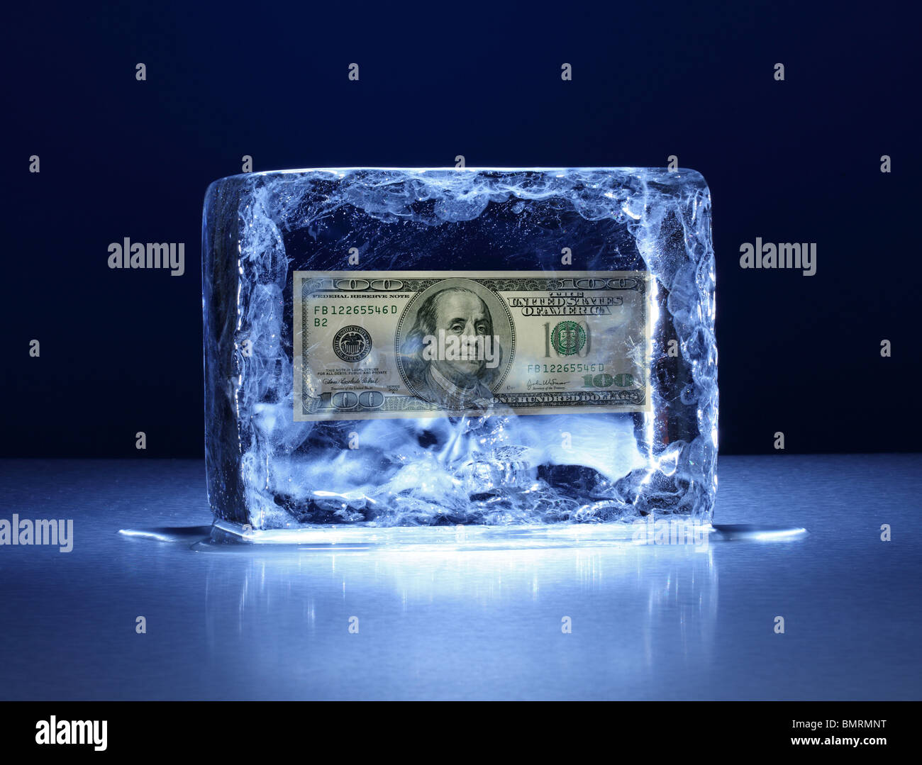 Un blocco congelato di ghiaccio su una superficie metallica con 100 USD dollaro all'interno di banconote Foto Stock