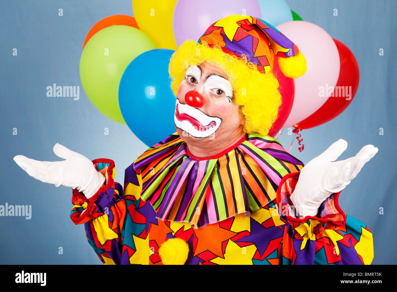Triste clown getta le sue mani nella disperazione. Il contrasto tra il costume di divertimento e di espressione infelice. Foto Stock