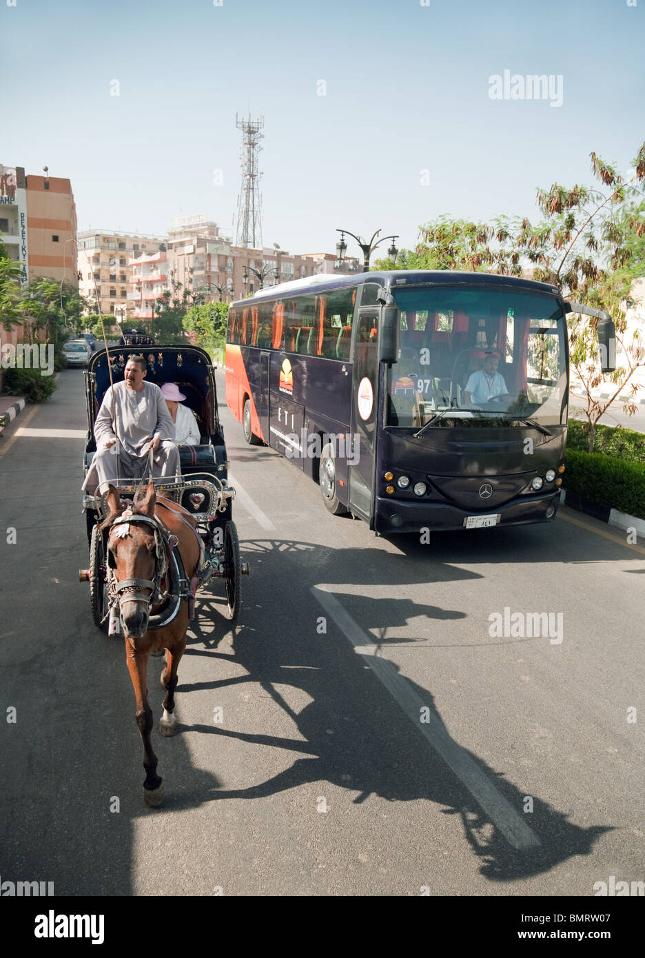 Un moderno pullman turistico passa i turisti in un tradizionale cavallo e carrozza (Hantoor), Luxor, l'Alto Egitto Foto Stock