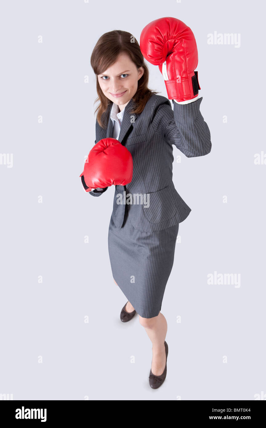 Imprenditrice cercando e indossando guanti di inscatolamento con sorriso Foto Stock