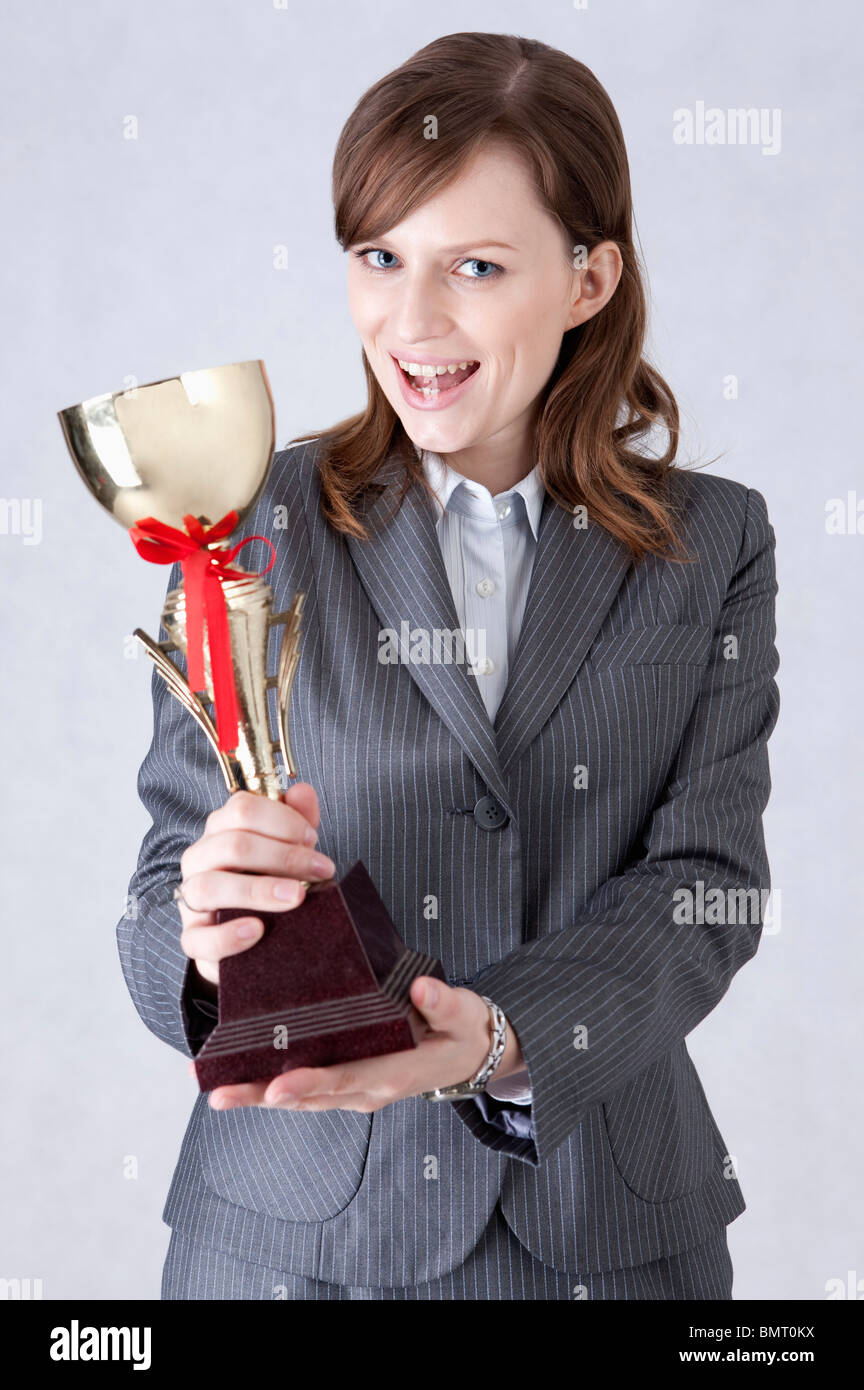 Imprenditrice che mostra un trofeo e sorridente Foto Stock