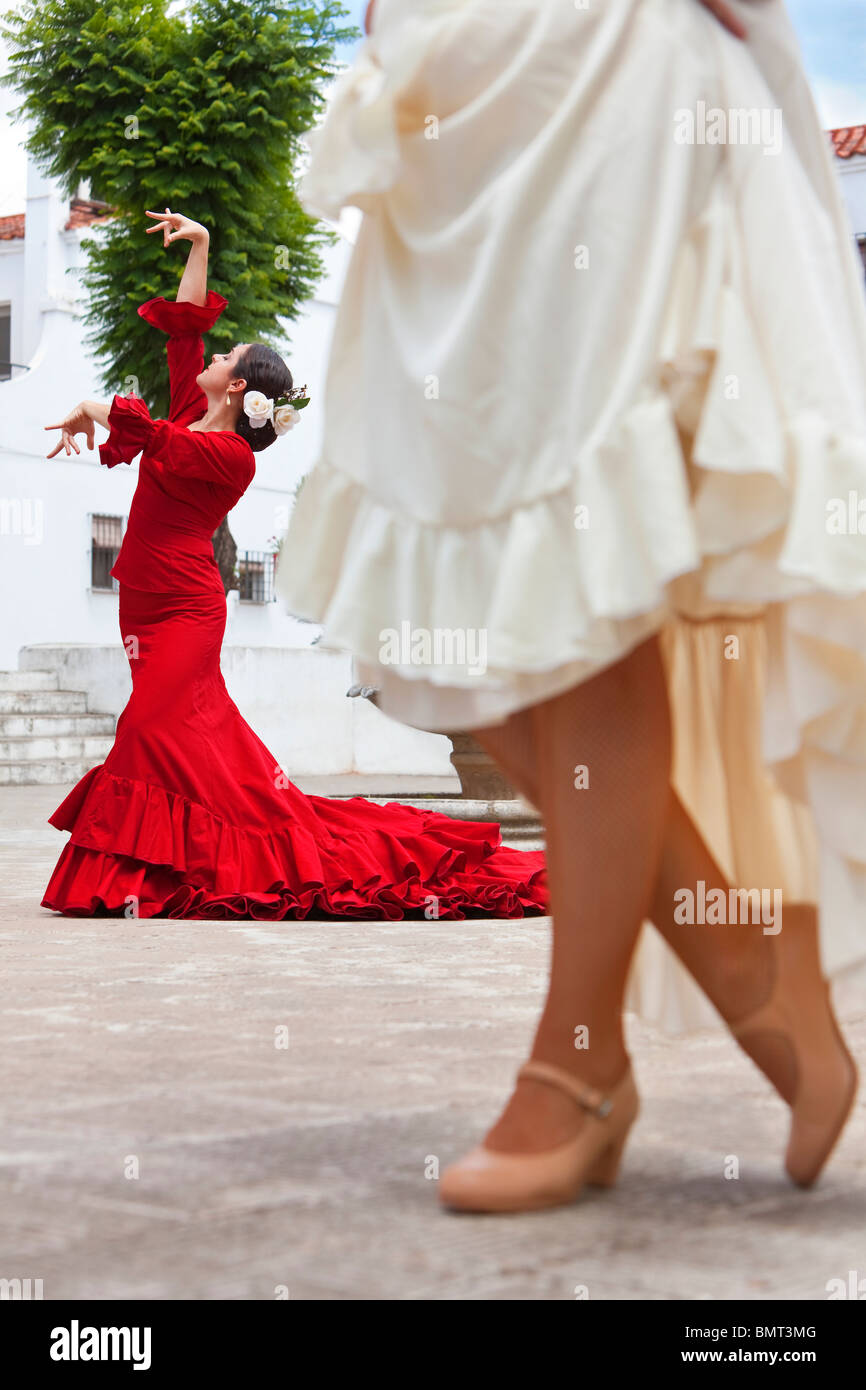 Due donne tradizionale spagnolo ballerini di flamenco dancing in una piazza cittadina, il focus è sul ballerino in abito rosso Foto Stock