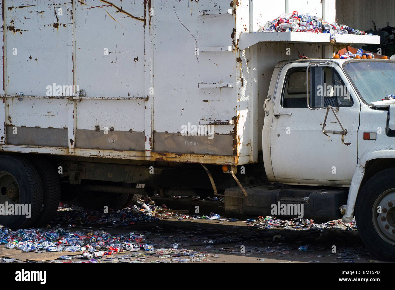 Un bianco carrello di trasporto viene caricato e cosparso con il suo carico di lattine in alluminio pronto per la frantumazione e riciclaggio. Foto Stock