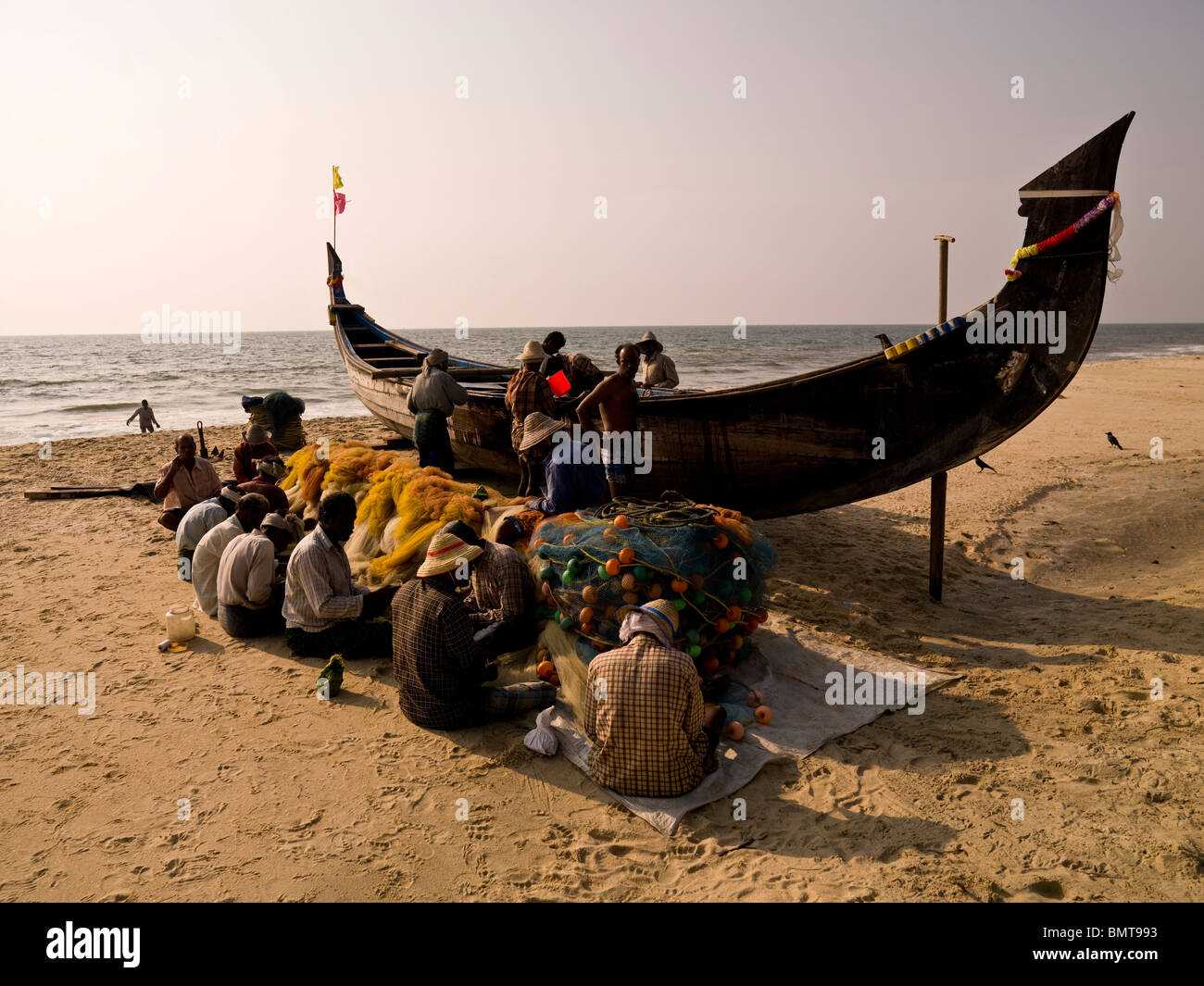 Il Kerala, India;i pescatori operanti sulle reti da pesca sulla spiaggia Foto Stock