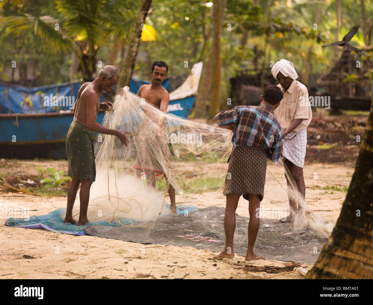 Il Kerala, India;pescatori Untangling reti da pesca sulla spiaggia Foto Stock