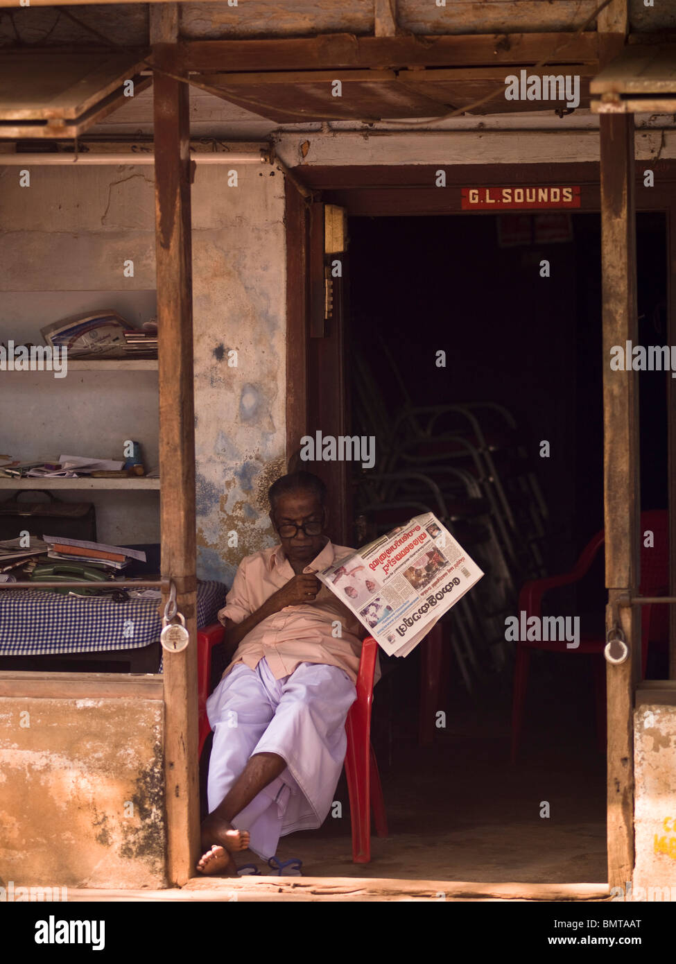 Alleppey,Kerala, India;l'uomo leggendo un giornale di fronte a una porta Foto Stock