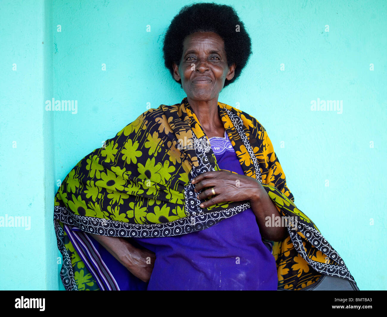 Black lady in blu che indossa un giallo e verde coperta fiorita in Ruanda dopo il genocidio Foto Stock