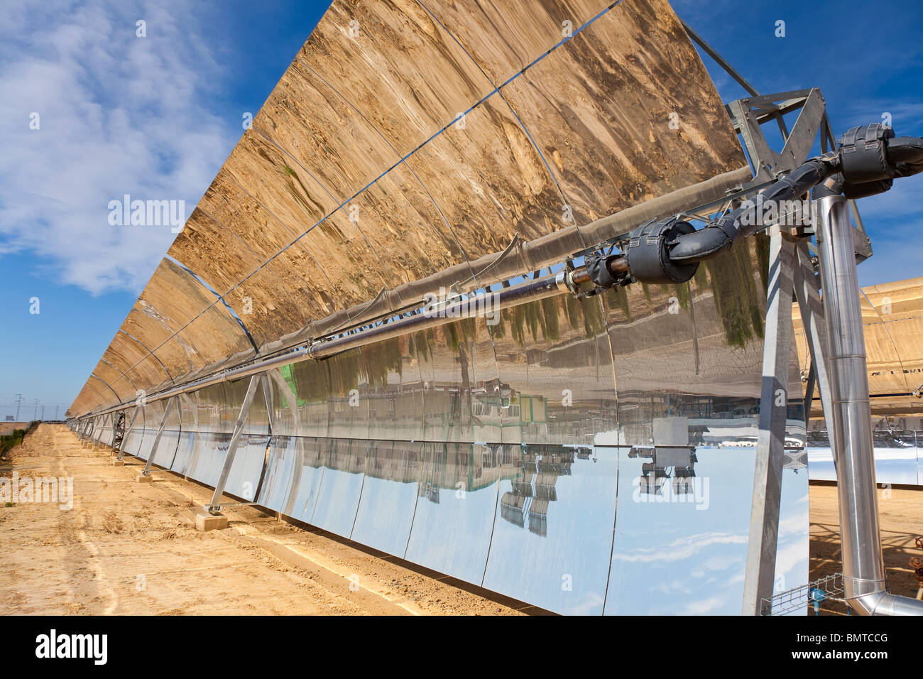 Una fila di parabolici pannelli a specchio sfruttando i raggi del sole per fornire fonti alternative di energia verde Foto Stock