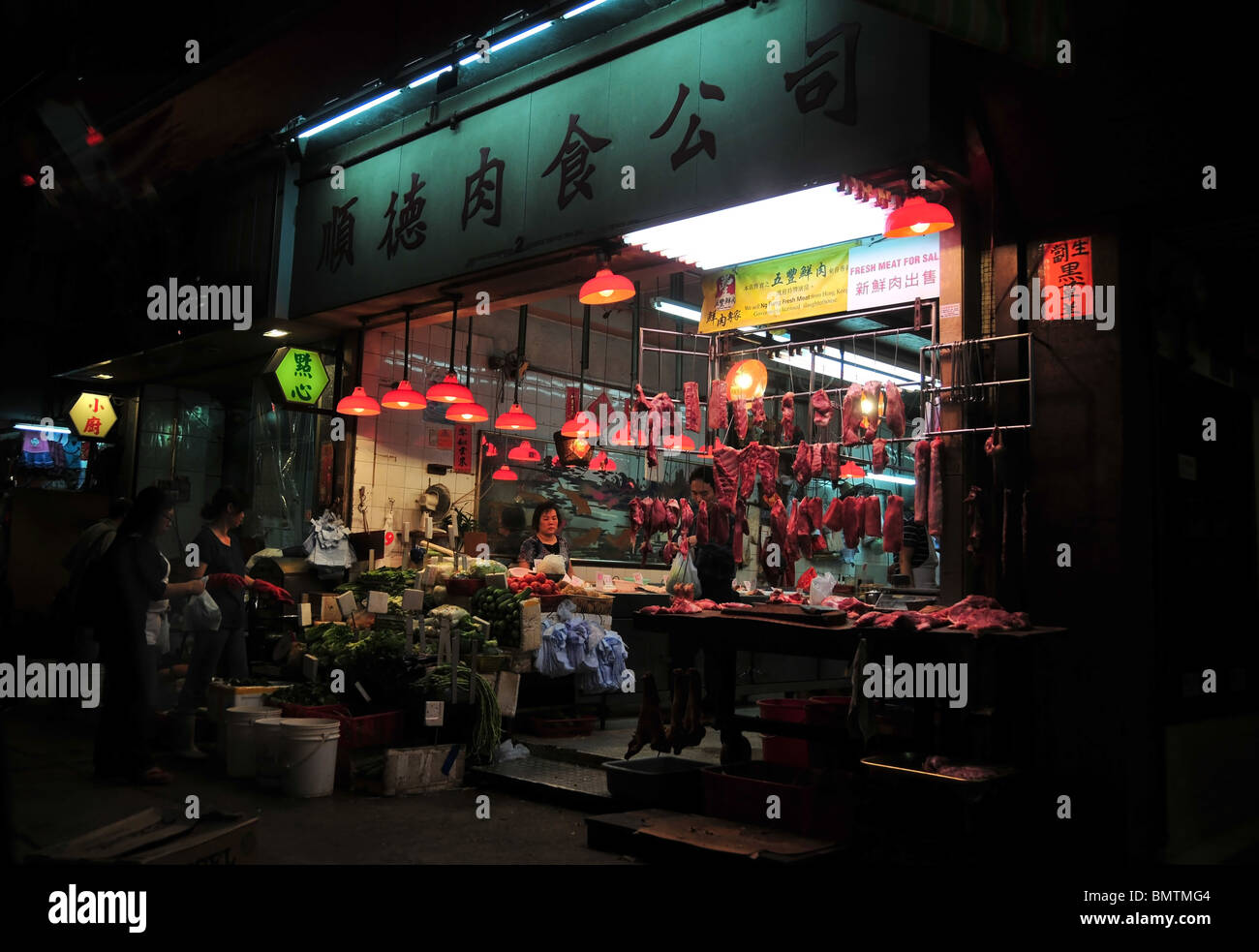 Di notte, angolo di strada colpo di illuminate al neon macelleria, la vendita di carni fresche provenienti da un macello del governo di Hong Kong Foto Stock