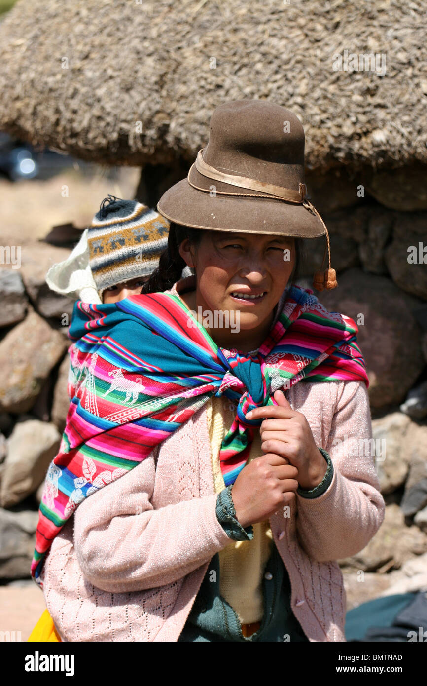 Donna Peruviana e bambino di abbigliamento tradizionale in una fattoria vicino a Sillustani, Lago Umayo vicino a Puno, Perù. Foto Stock
