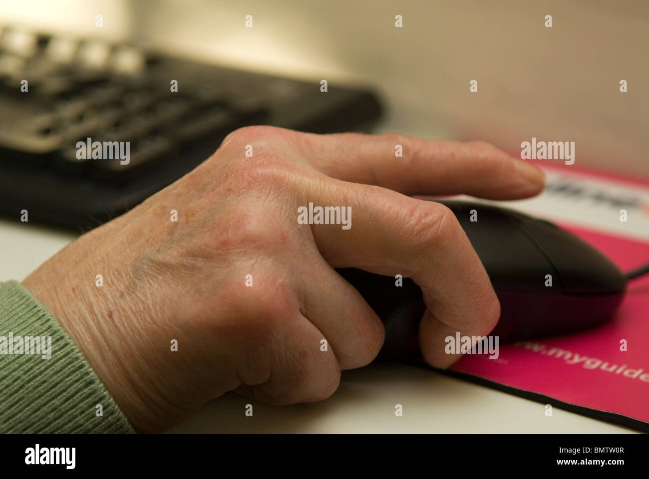 Donna anziana con una mano sul mouse mentre si naviga in internet, Peckham, Londra, Regno Unito. Foto Stock