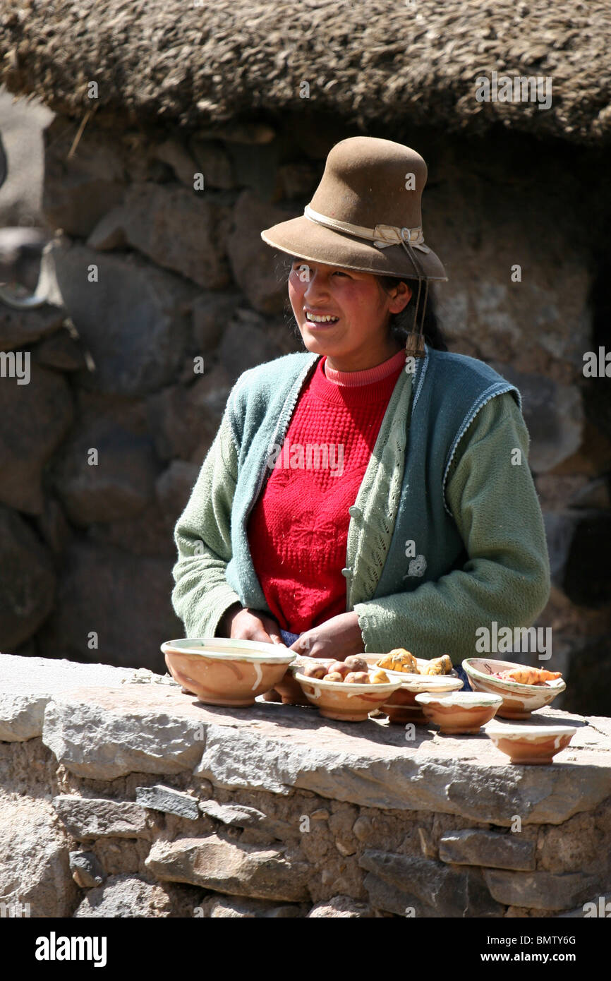 Donna Peruviana in abbigliamento tradizionale dimostrando prodotti locali presso un agriturismo vicino a Sillustani, Lago Umayo vicino a Puno, Perù. Foto Stock