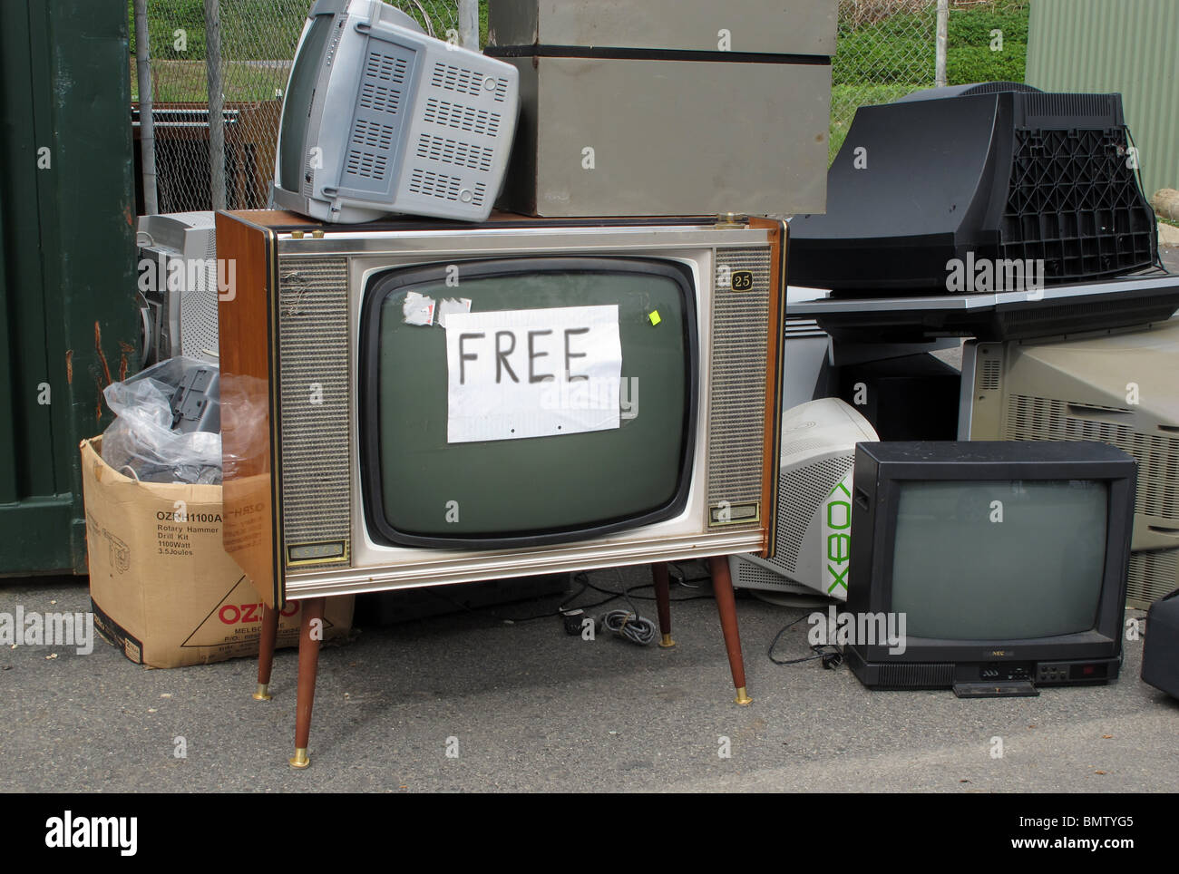 Una televisione vintage è offerto gratuitamente a un consiglio di rifiutare i rifiuti in discarica. Foto Stock