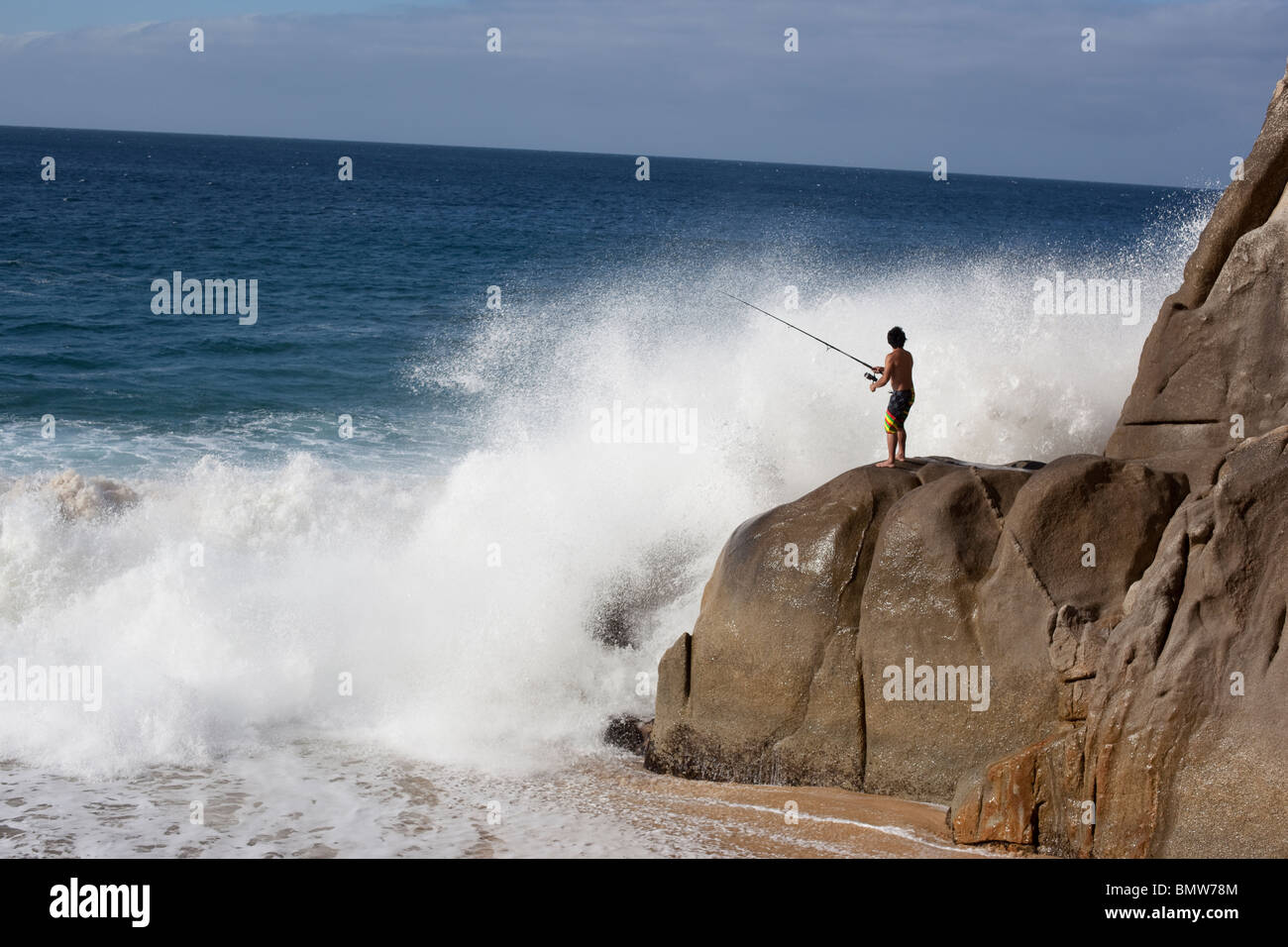 L'uomo la pesca Rocks off con grandi onde in Messico Foto Stock