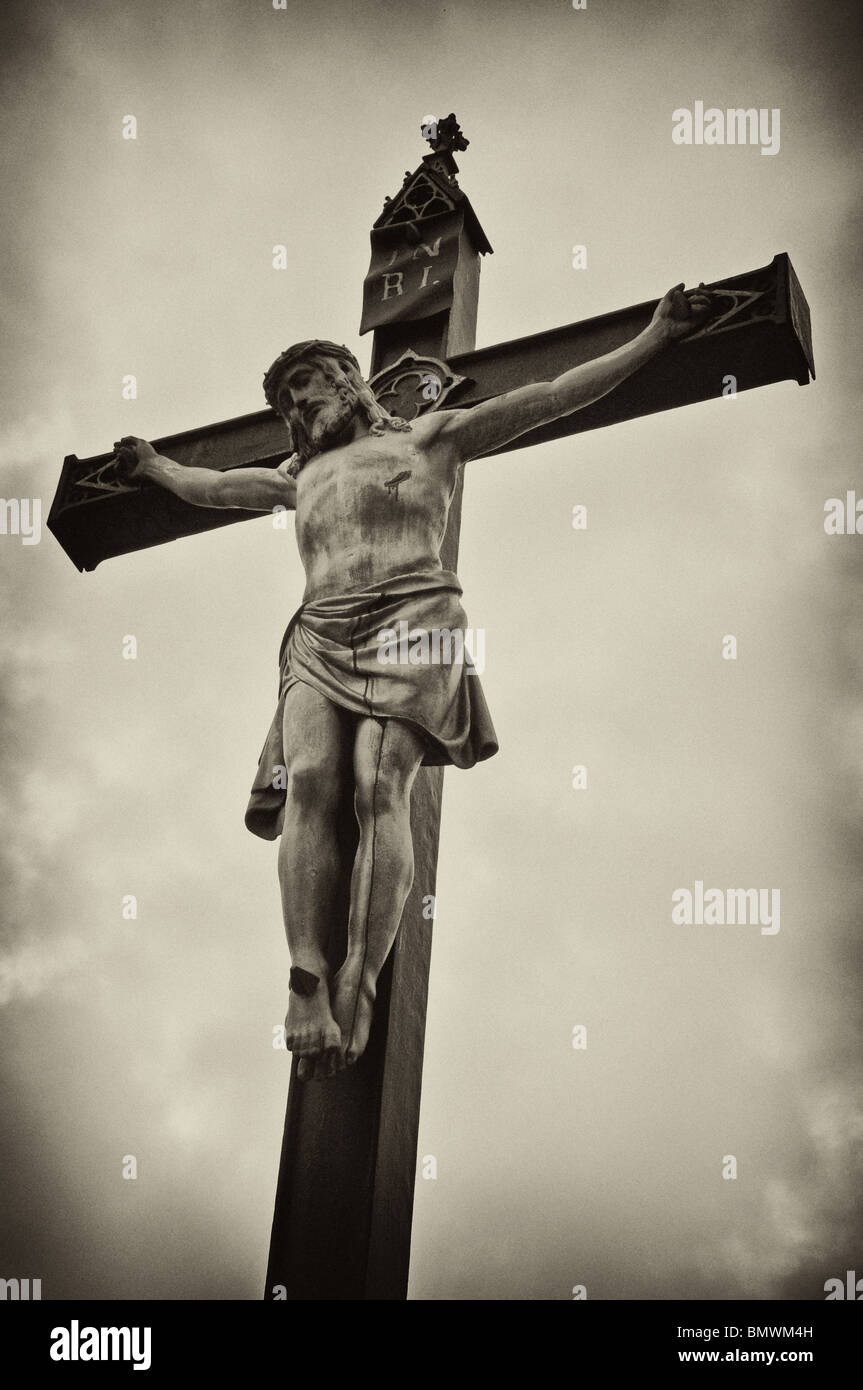 Una statua di Gesù Cristo crocifisso su una croce su un sfondo grunge, foto in bianco e nero. Foto Stock
