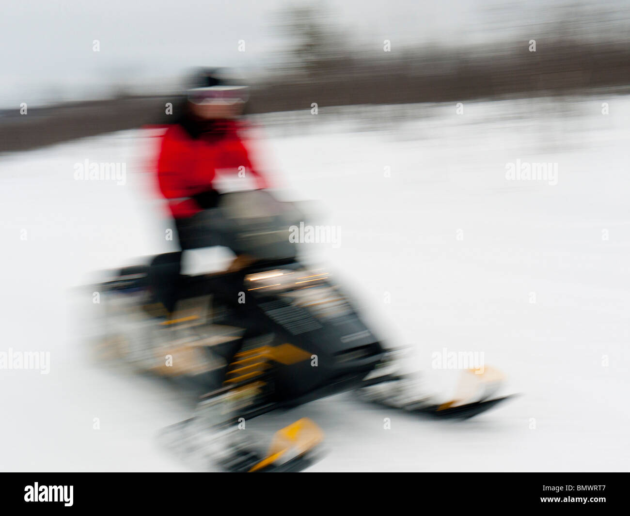 Un giovane uomo aziona una motoslitta attraverso la neve a Kiruna, Lapponia, Svezia settentrionale. Foto Stock