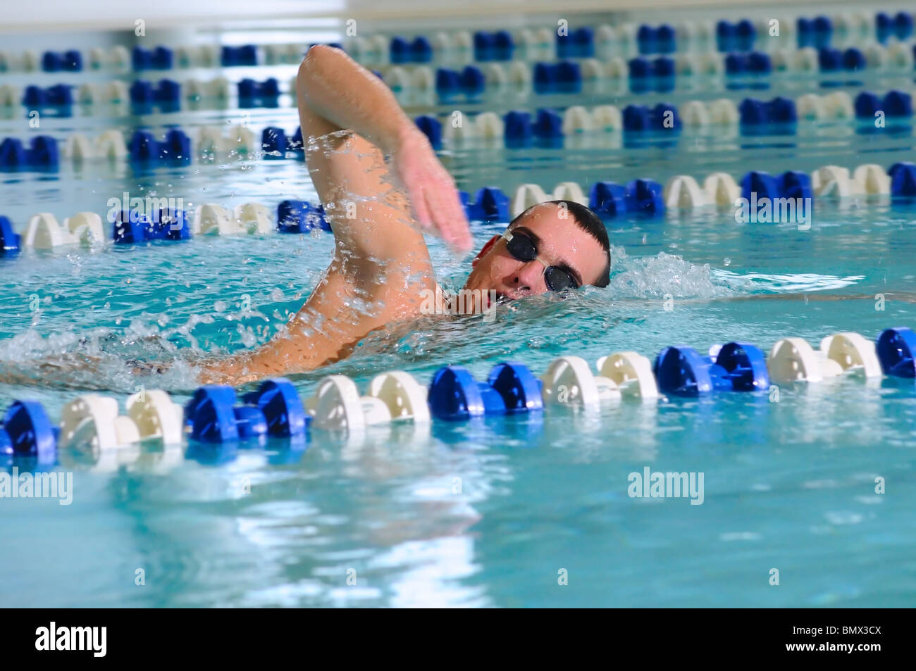L'uomo nuota usando il crawl corsa in piscina interna Foto Stock
