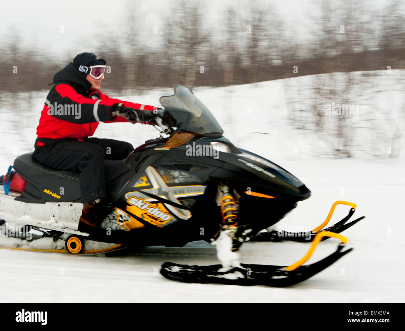 Un giovane uomo aziona una motoslitta attraverso la neve a Kiruna, Lapponia, Svezia settentrionale. Foto Stock