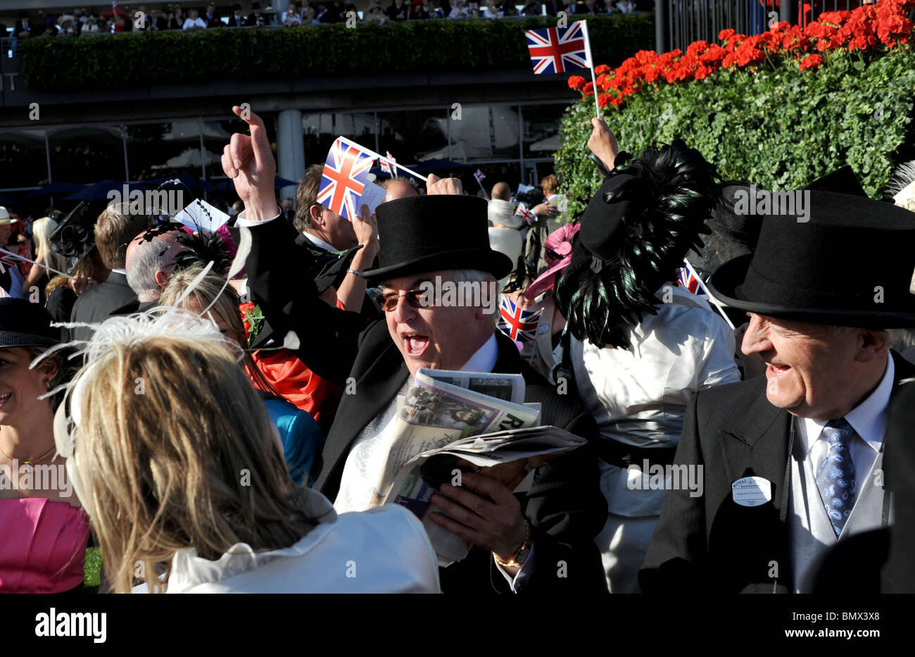 Royal Ascot Berkshire - Racegoers gustare il tradizionale fine del giorno singsong al palco per spettacoli con union jack flag a onda Foto Stock