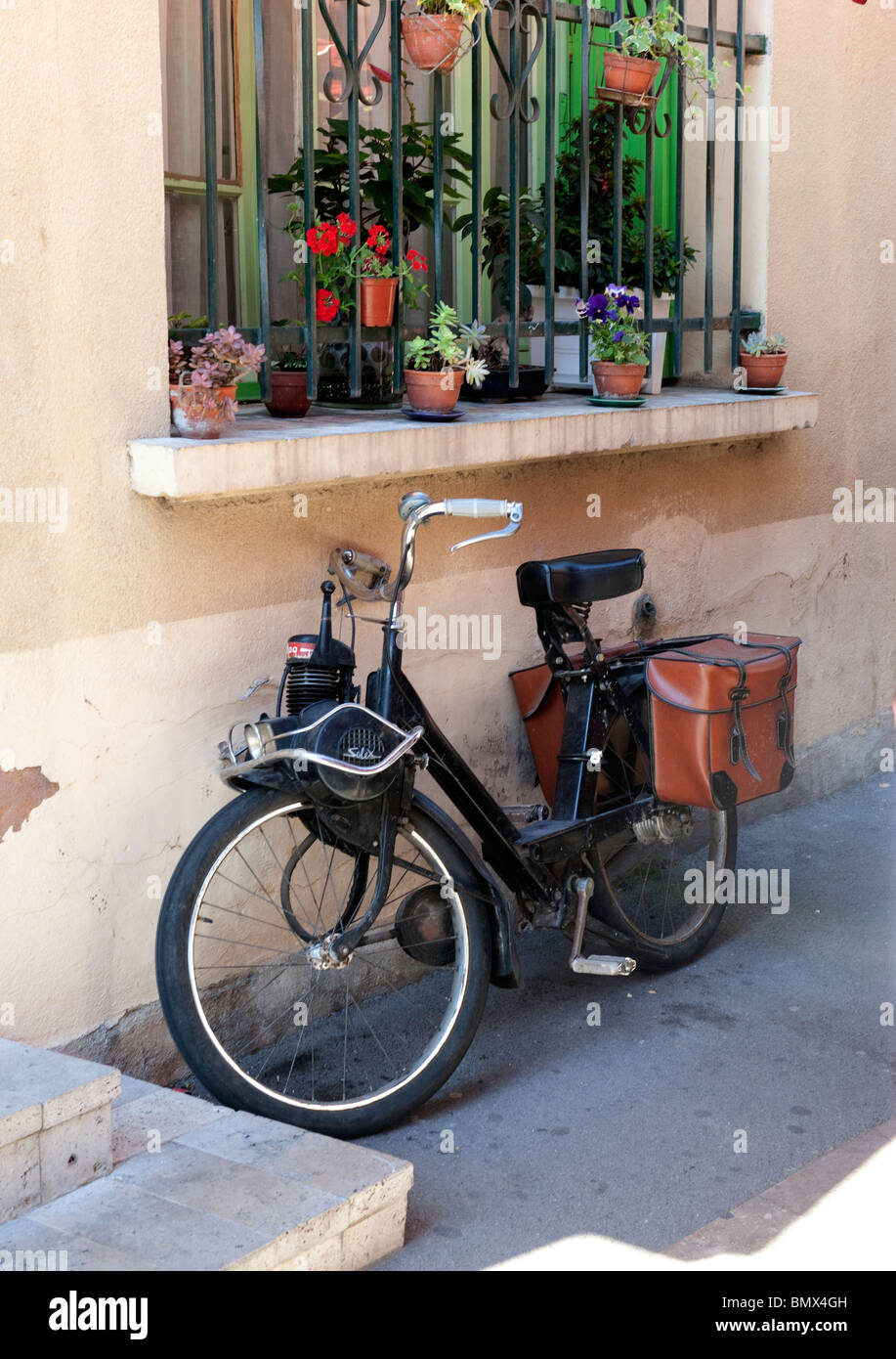 Vecchio motorino ciclismo appoggiato contro una parete nel grazioso villaggio francese nel Sud della Francia Foto Stock