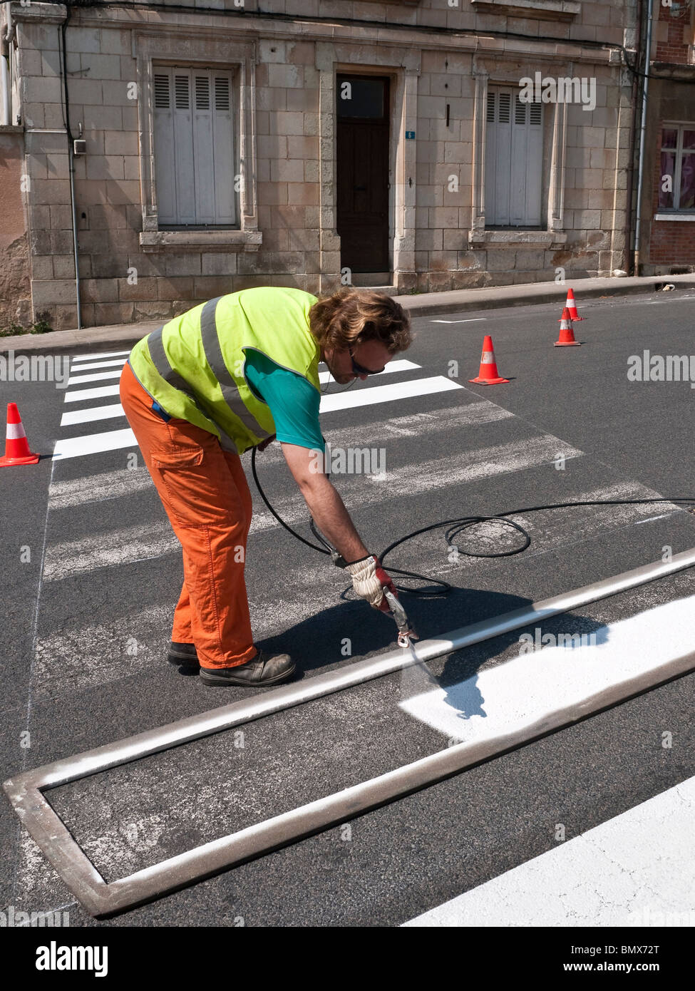 Roadworker riverniciatura di attraversamento pedonale strisce sulla superficie stradale - Francia. Foto Stock