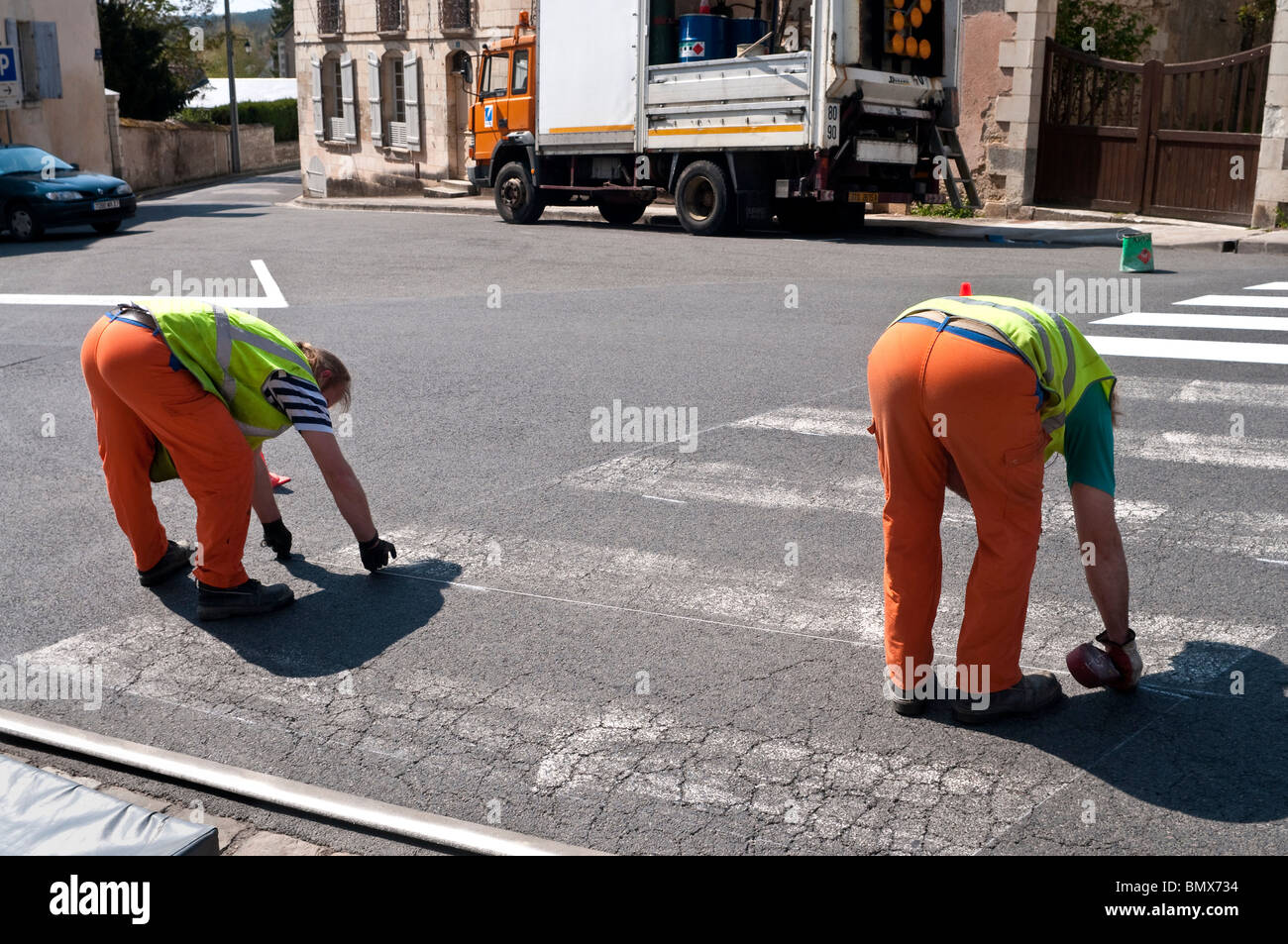 Roadworkers riverniciatura di attraversamento pedonale strisce sulla superficie stradale - Francia. Foto Stock