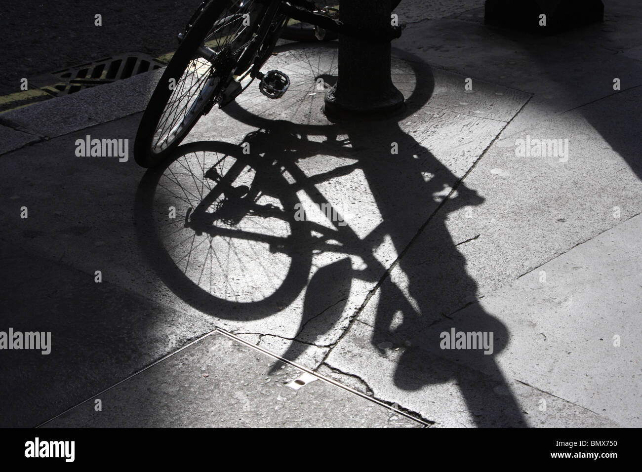 Ombra proiettata da una bicicletta parcheggiata contro un lampione di Soho, London, W1. Foto Stock
