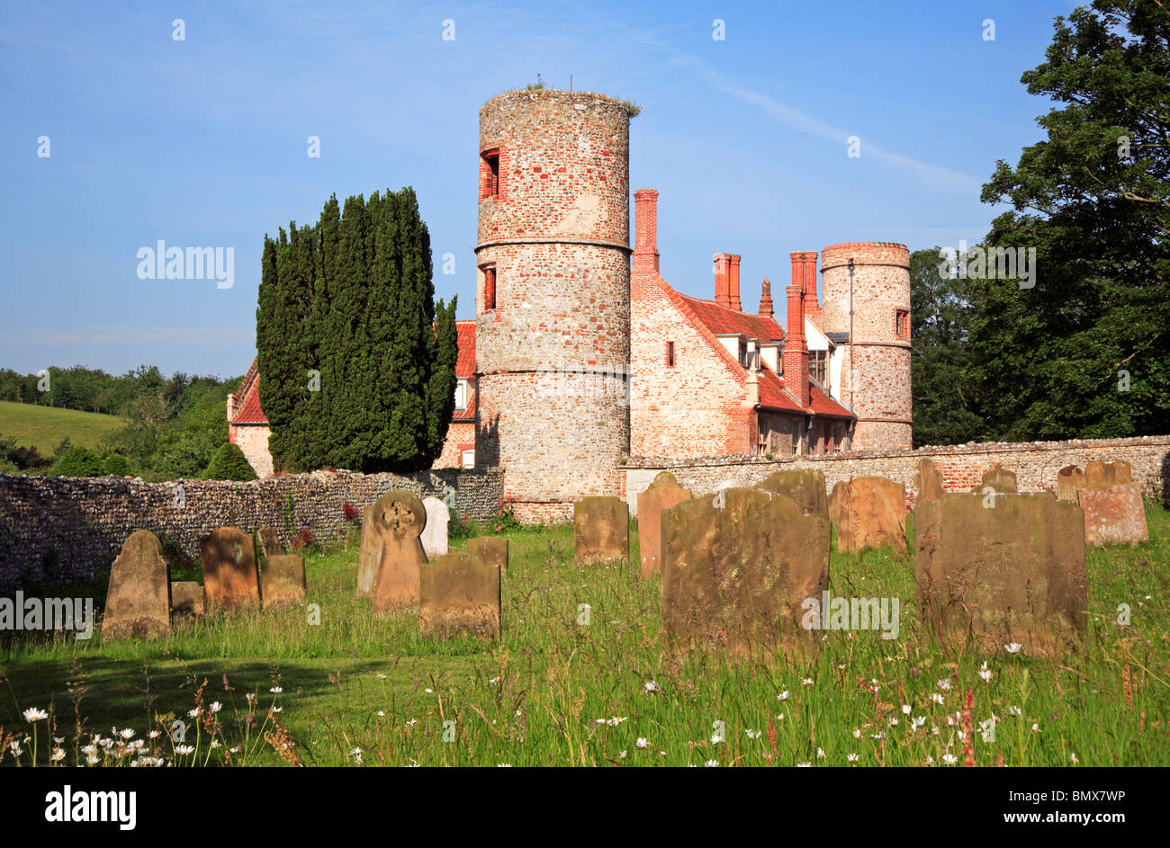 Un angolo del sagrato della chiesa di San Giovanni Battista a Stiffkey, Norfolk, Inghilterra, con la vecchia sala. Foto Stock