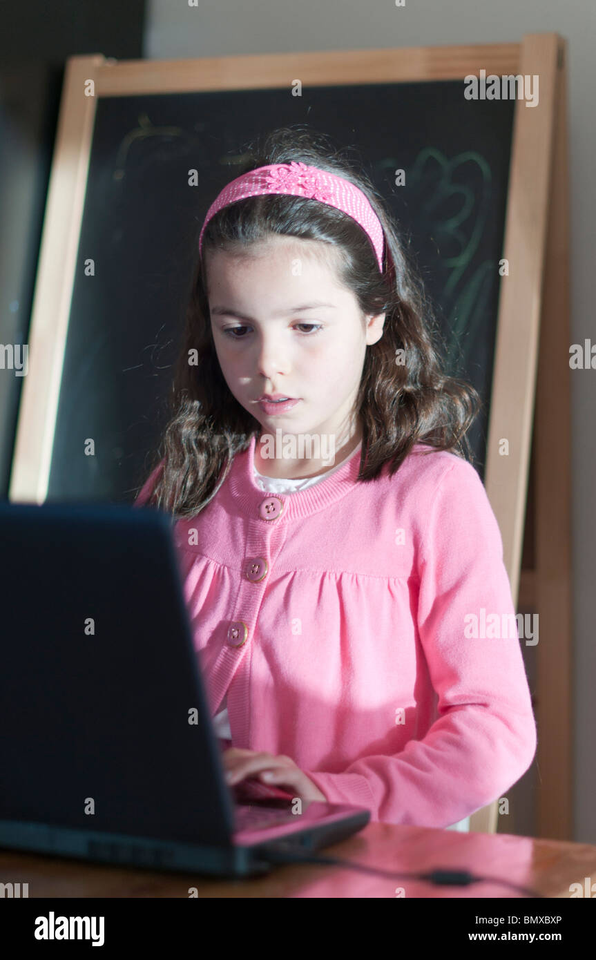 Ragazza,8 anni durante la navigazione in internet su un computer portatile Foto Stock