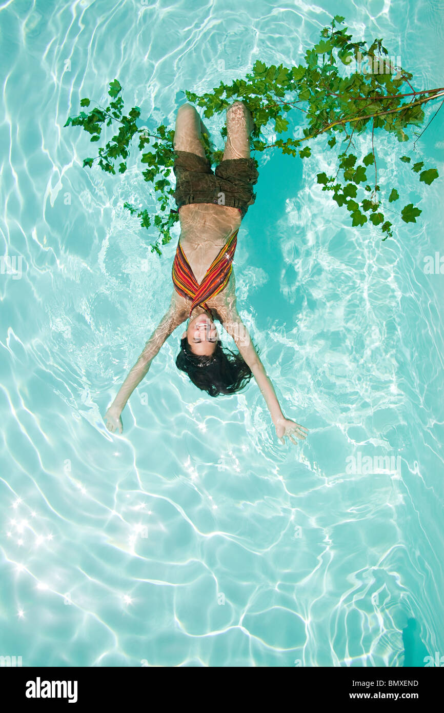 Donna appeso a testa in giù dal ramo in piscina Foto Stock