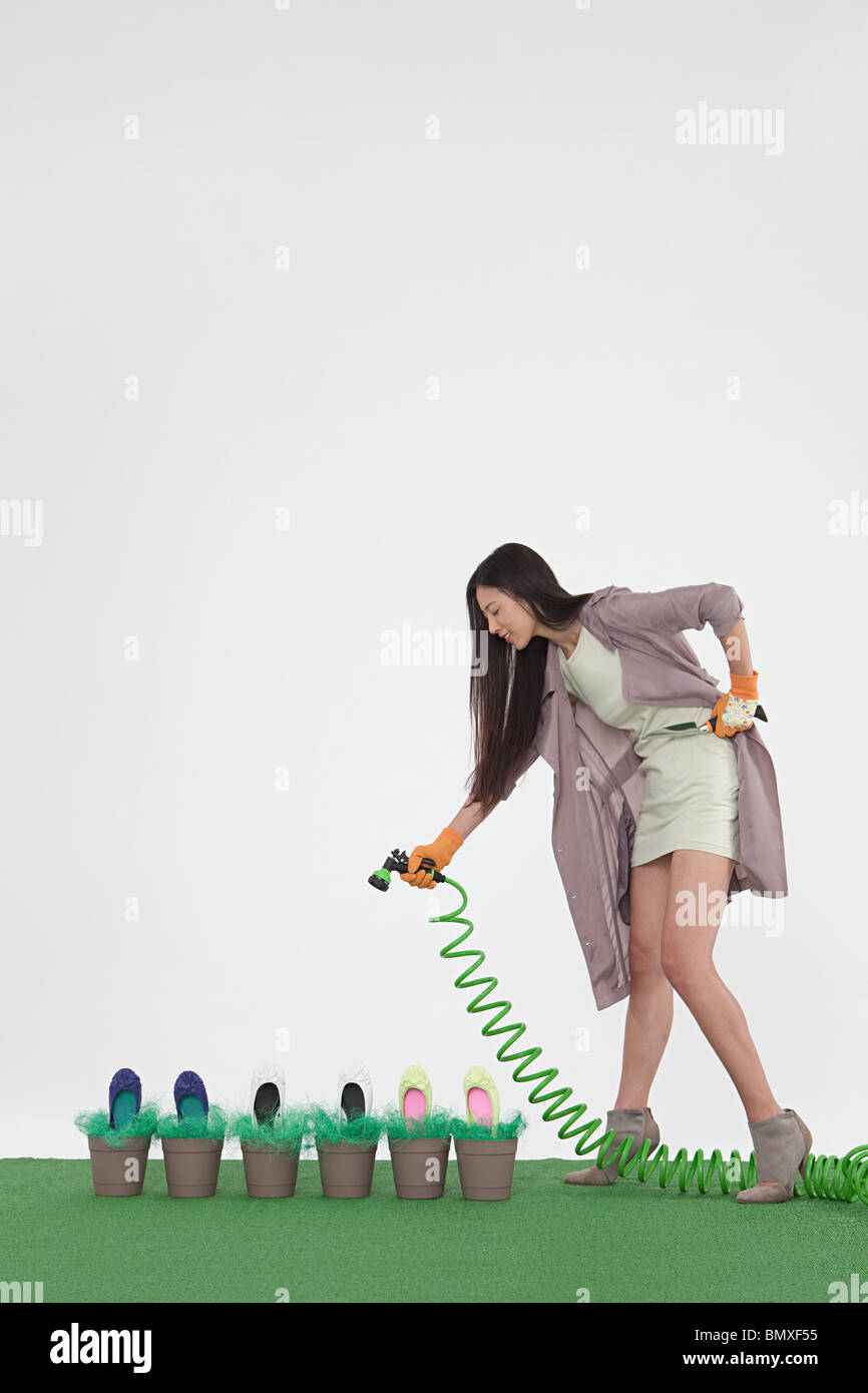 Donna con tubo flessibile e scarpe in vasi di fiori Foto Stock