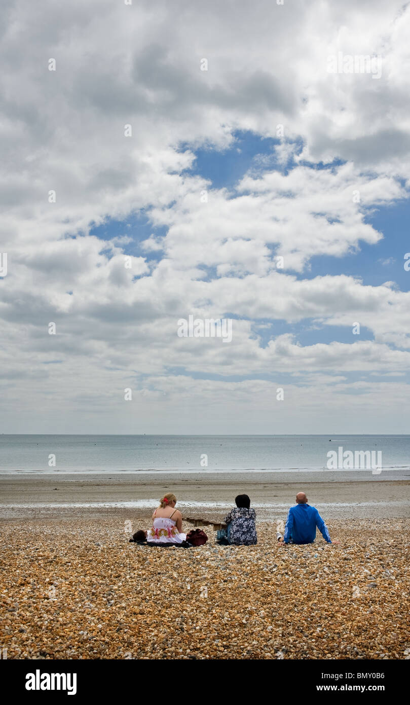 Tre persone sedute su una spiaggia di ciottoli. Foto di Gordon Scammell Foto Stock