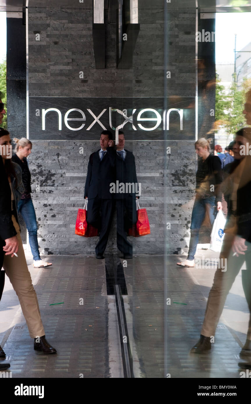 Uomo con red borsa di trasporto nella parte anteriore del prossimo negozio su Oxford Street, London, Regno Unito Foto Stock