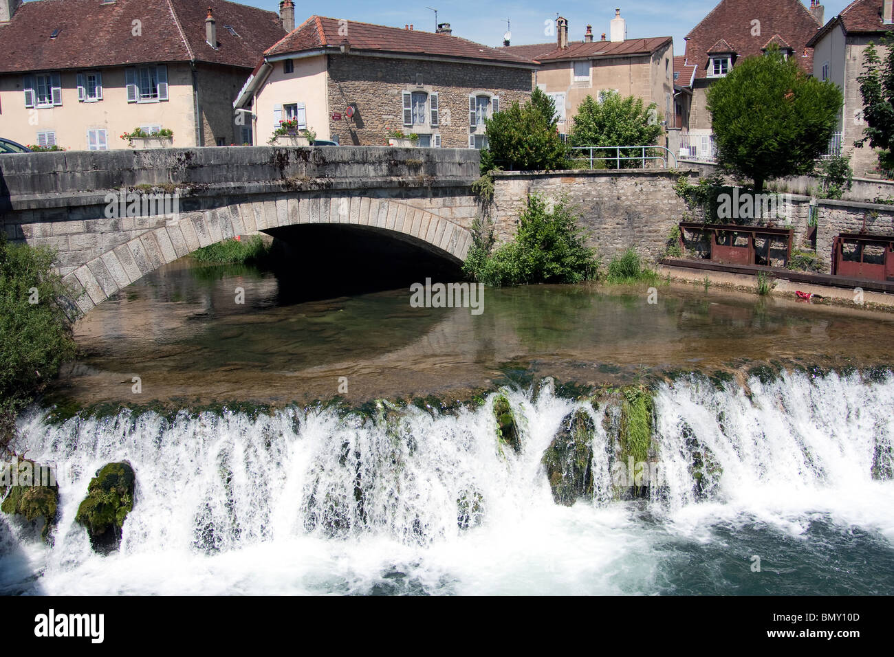 Fiume case alberi weir che scorre veloce ponte di acqua Foto Stock