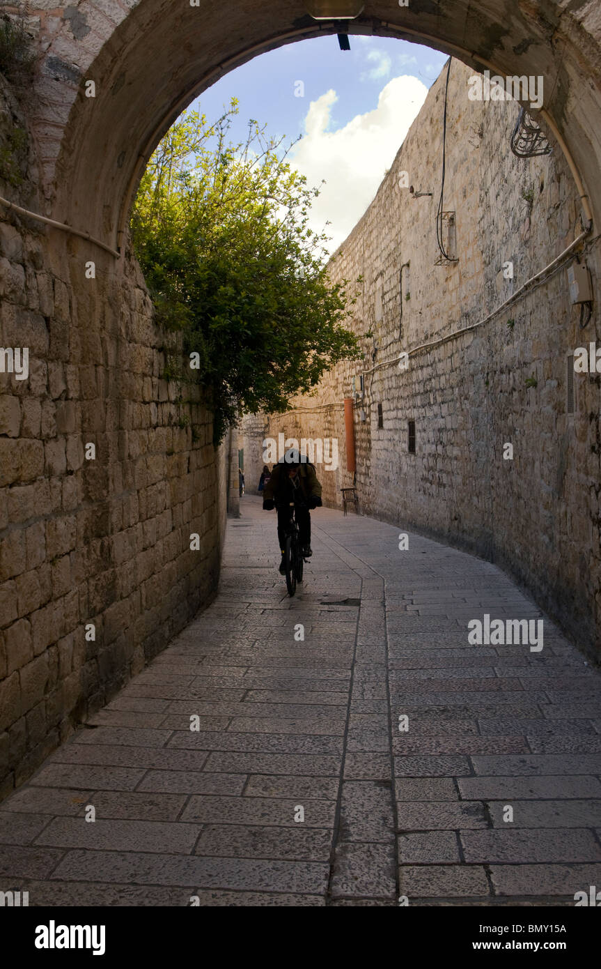 Un bicycler passando attraverso St James Street nel quartiere armeno la città vecchia di Gerusalemme Est Israele Foto Stock