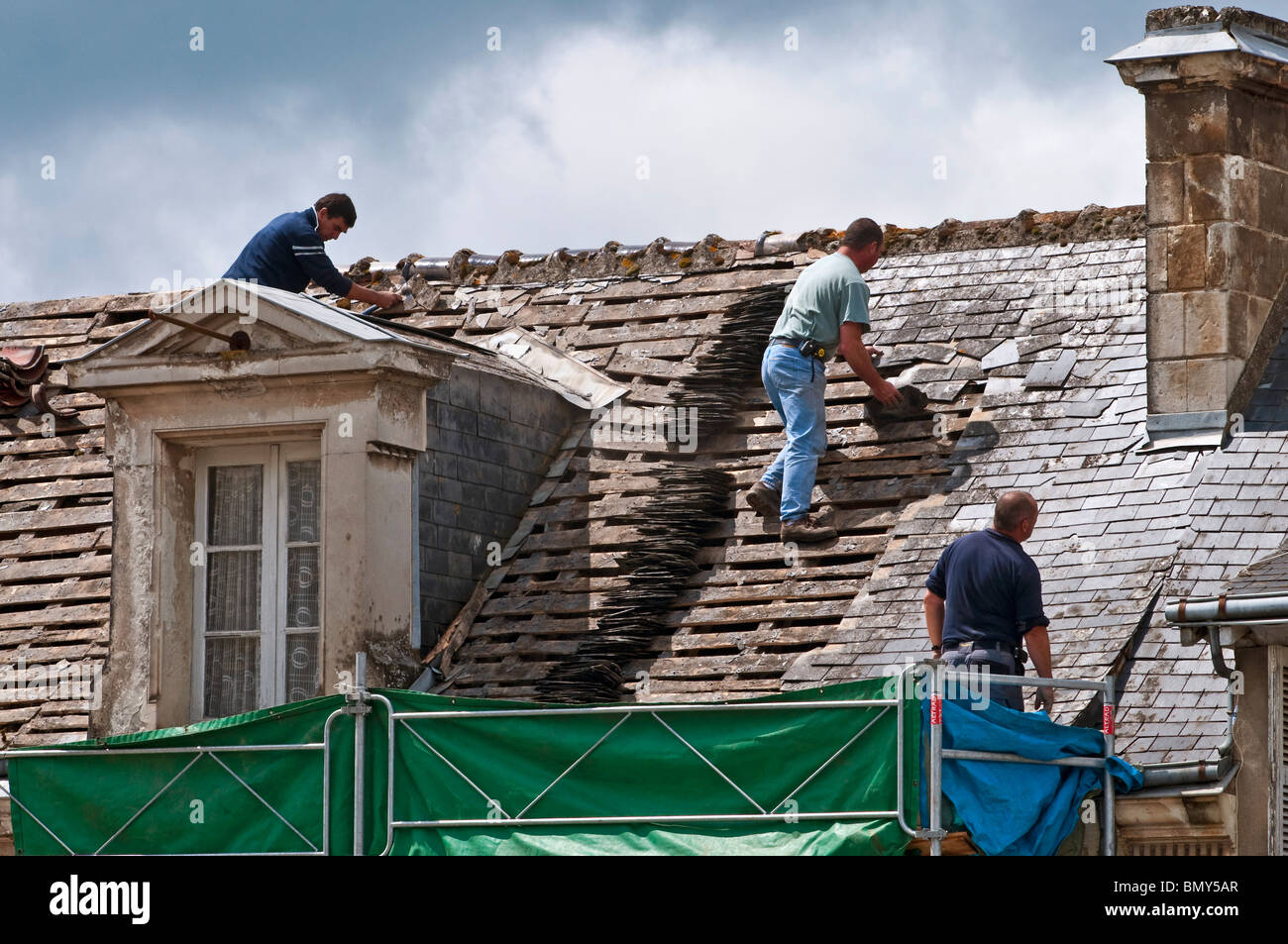 Lavoratori su town house tetto rimozione di vecchie ardesie / nessuna attrezzatura di sicurezza o caschi - Francia. Foto Stock