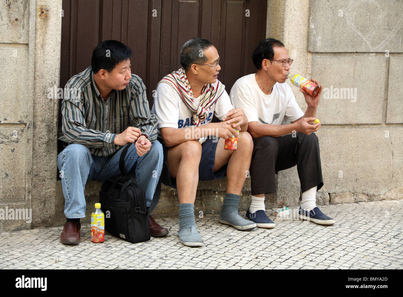 Gli uomini seduti su una soglia, Macao, Cina Foto Stock