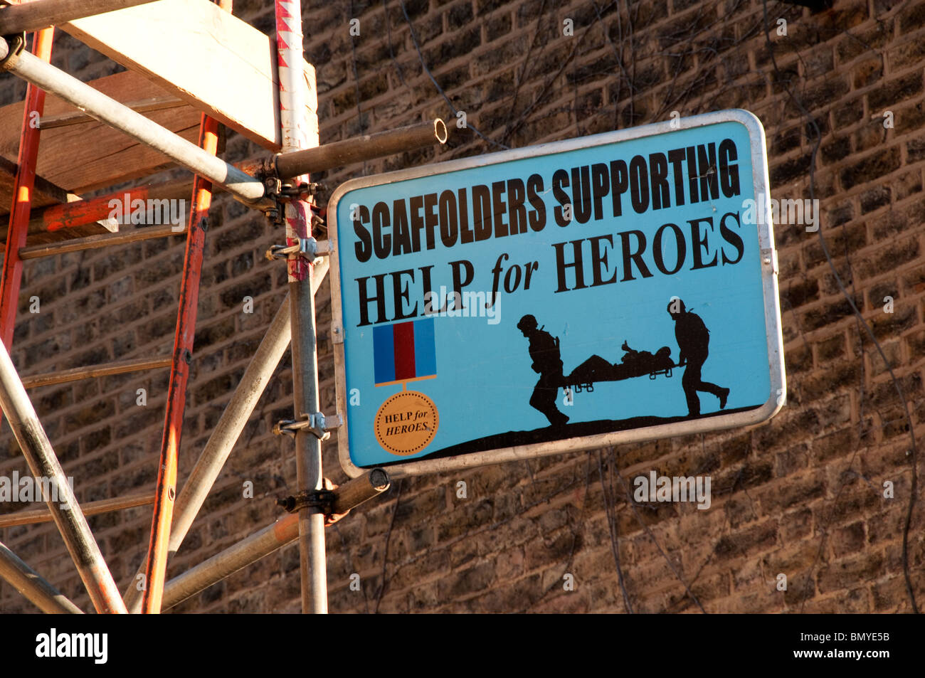 Scaffolders Guida di supporto per gli eroi segno su un edificio sito nella parte sud di Londra Foto Stock