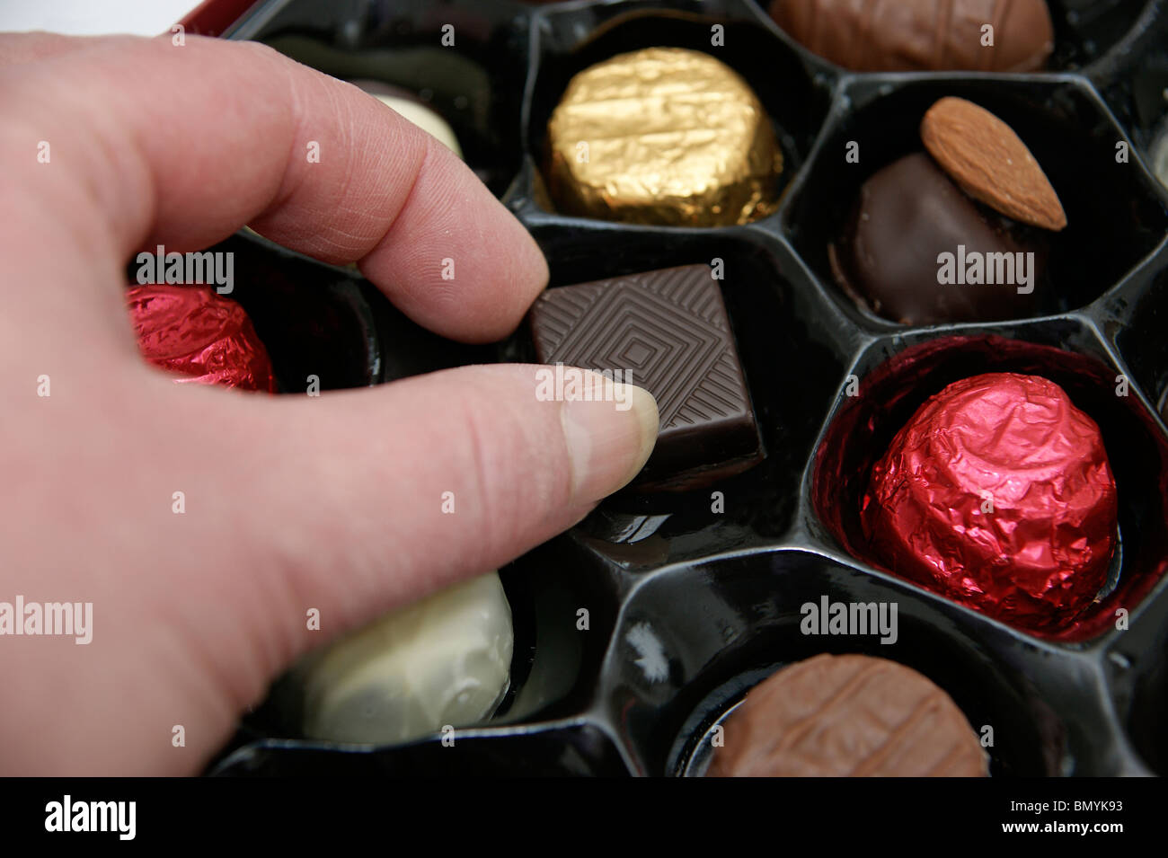 Donna aiutare se stessa ad un cioccolato da una scatola di cioccolatini Foto Stock