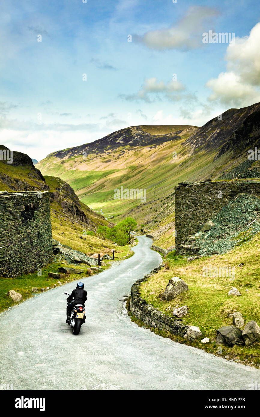 Motociclista sul viaggio su strada attraverso una strada di montagna su Honister Pass nel distretto del lago, England, Regno Unito Foto Stock