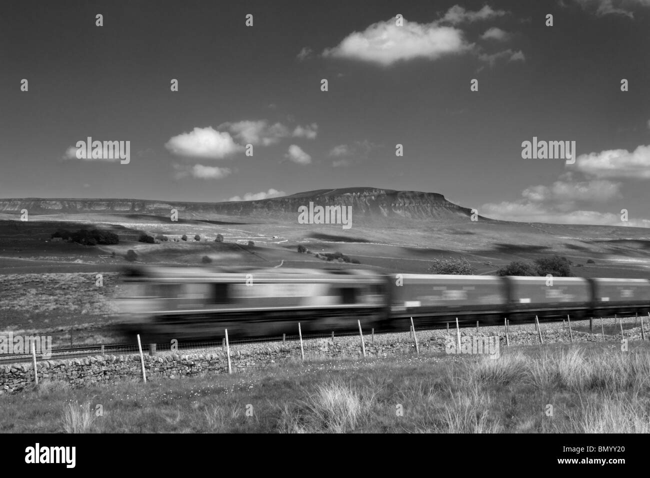 Un treno merci passa Penyghent, vicino Selside nel Yorkshire Dales National Park, Inghilterra. Foto Stock