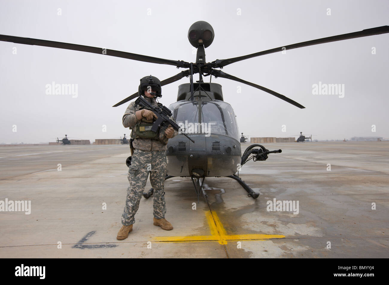 Un OH-58D Kiowa Warrior pilot sorge accanto al suo aeromobile. Foto Stock