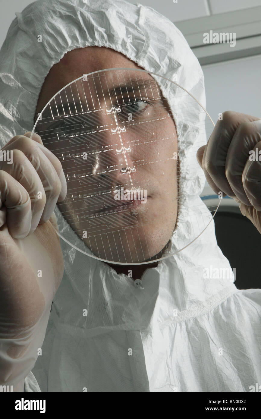 Scienziato di fabbricazione di ispezione di un vetro wafer microfluidico in una stanza pulita Foto Stock
