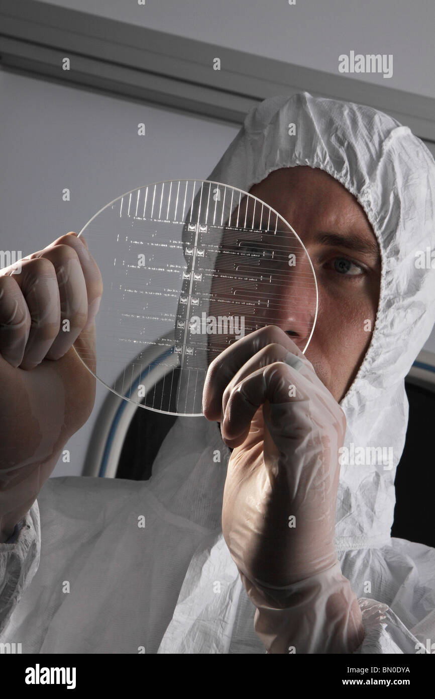 Scienziato di fabbricazione di ispezione di un vetro wafer microfluidico in una stanza pulita Foto Stock