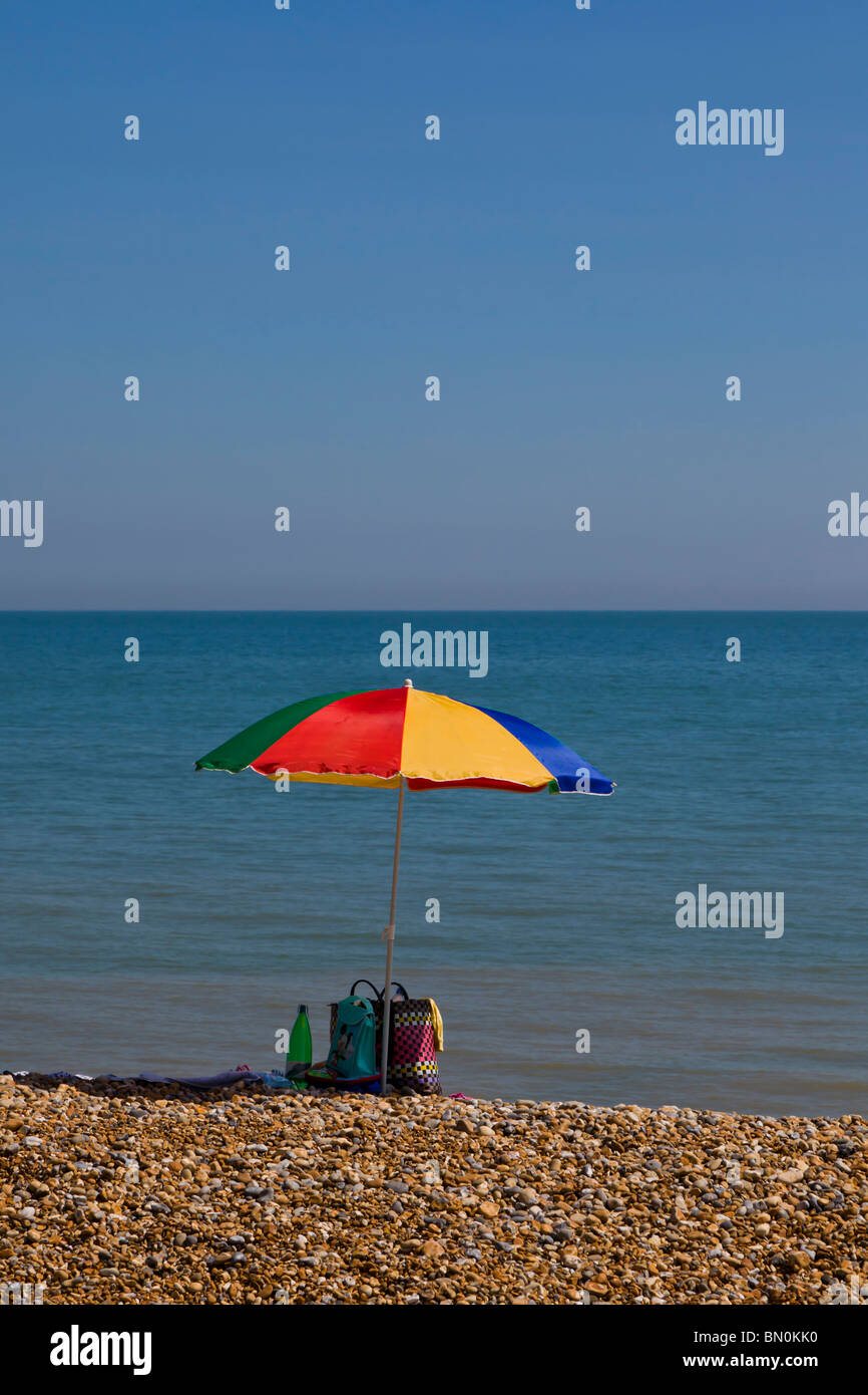 Ombrello coloratissimo isolato su una spiaggia con il mare sullo sfondo. Foto Stock