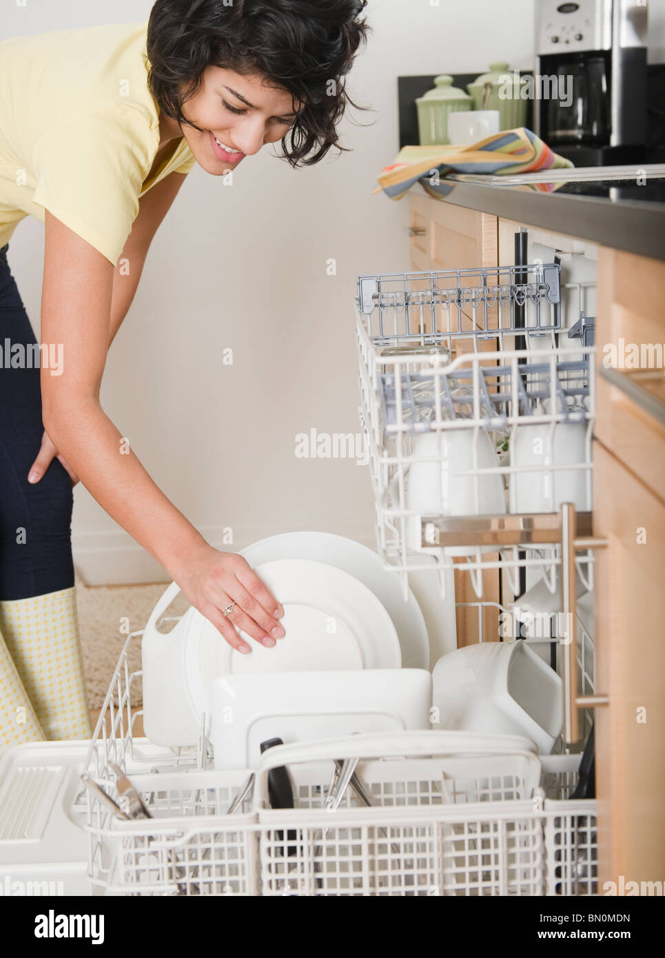 Donna ispanica di mettere i piatti in lavastoviglie Foto Stock