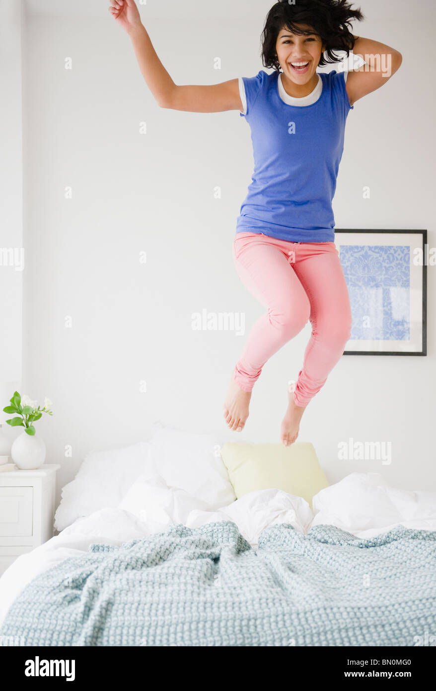 Donna ispanica saltando sul letto Foto Stock