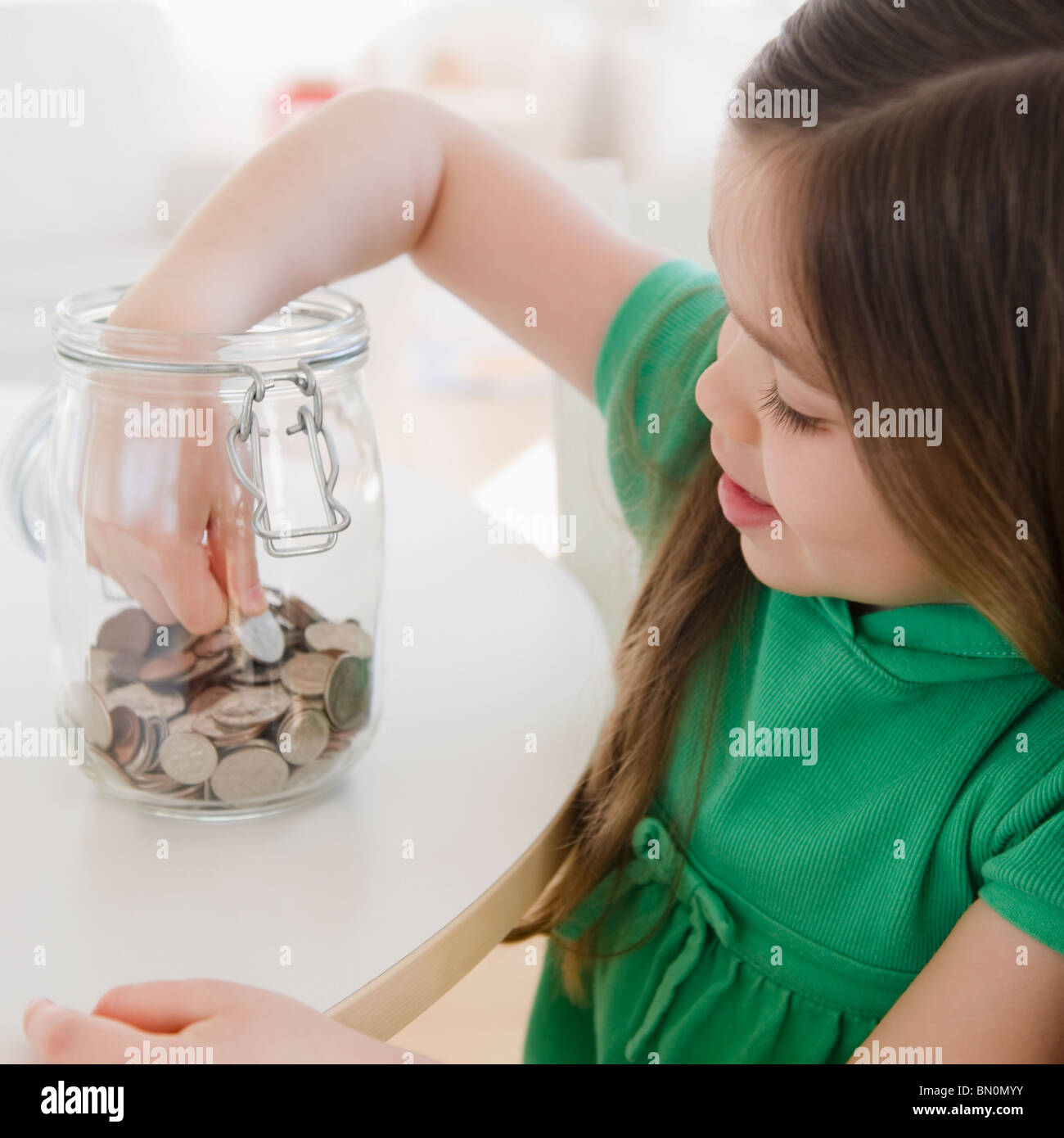 Razza mista ragazza tenendo moneta al di fuori del vaso Foto Stock