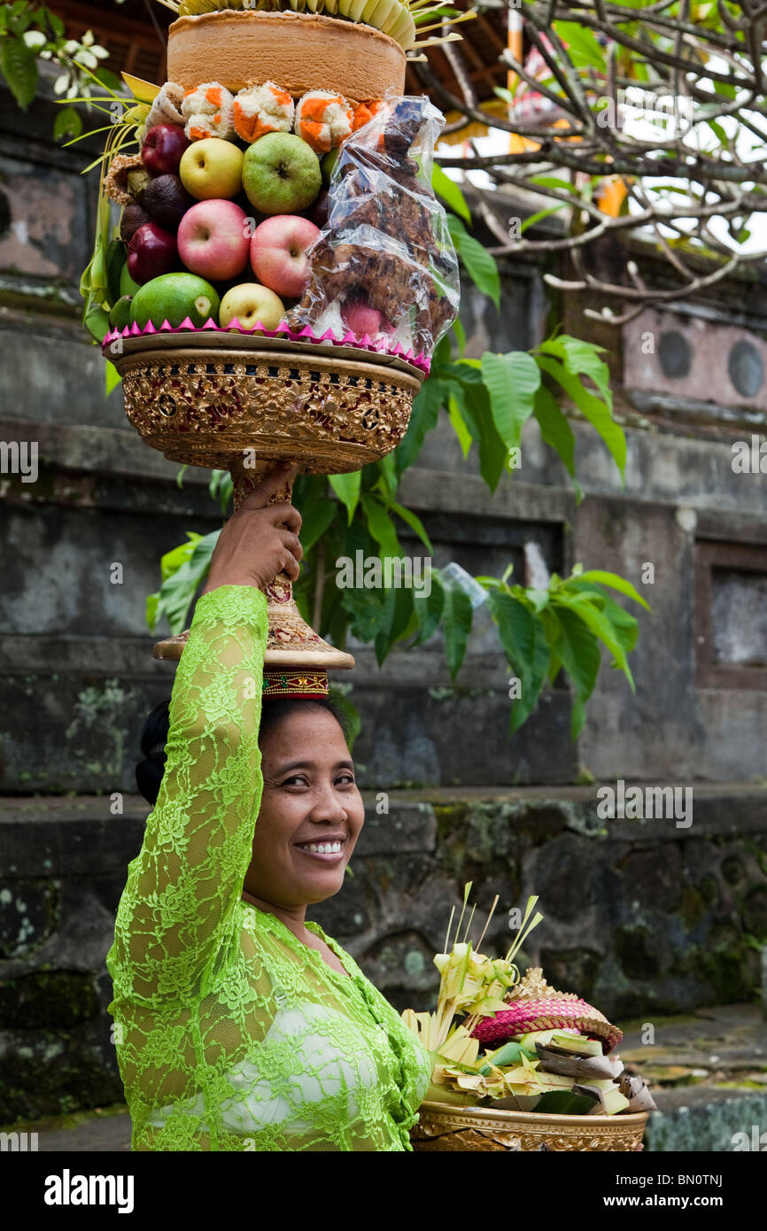 Donna Balinese con gebogan o disposti offerte di frutta, rendendo il loro modo di tempio indù a Buda Keliwon Pegatuwakan Foto Stock