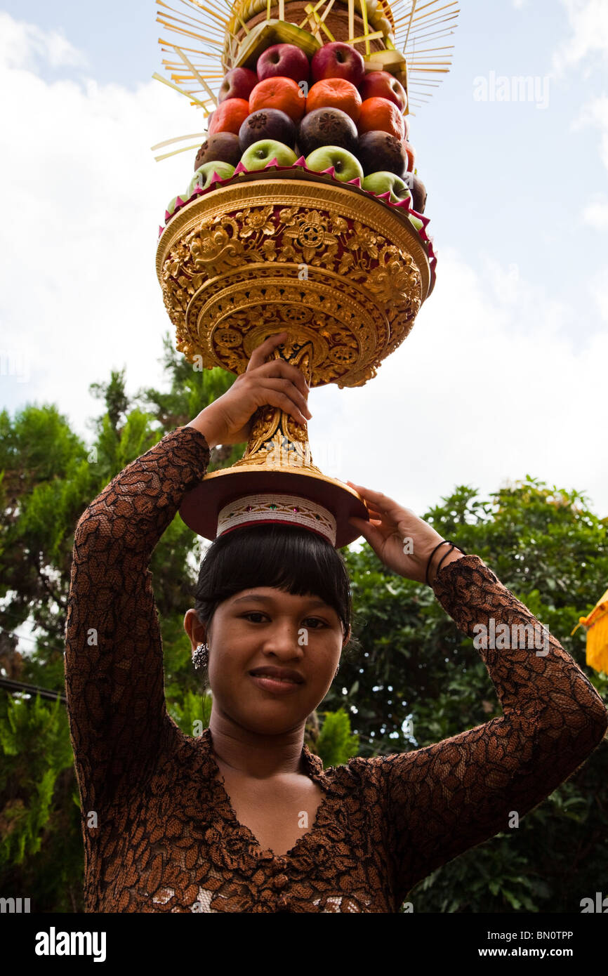 Donna Balinese con gebogan o disposti offerte di frutta, rendendo il loro modo di tempio indù a Buda Keliwon Pegatuwakan Foto Stock